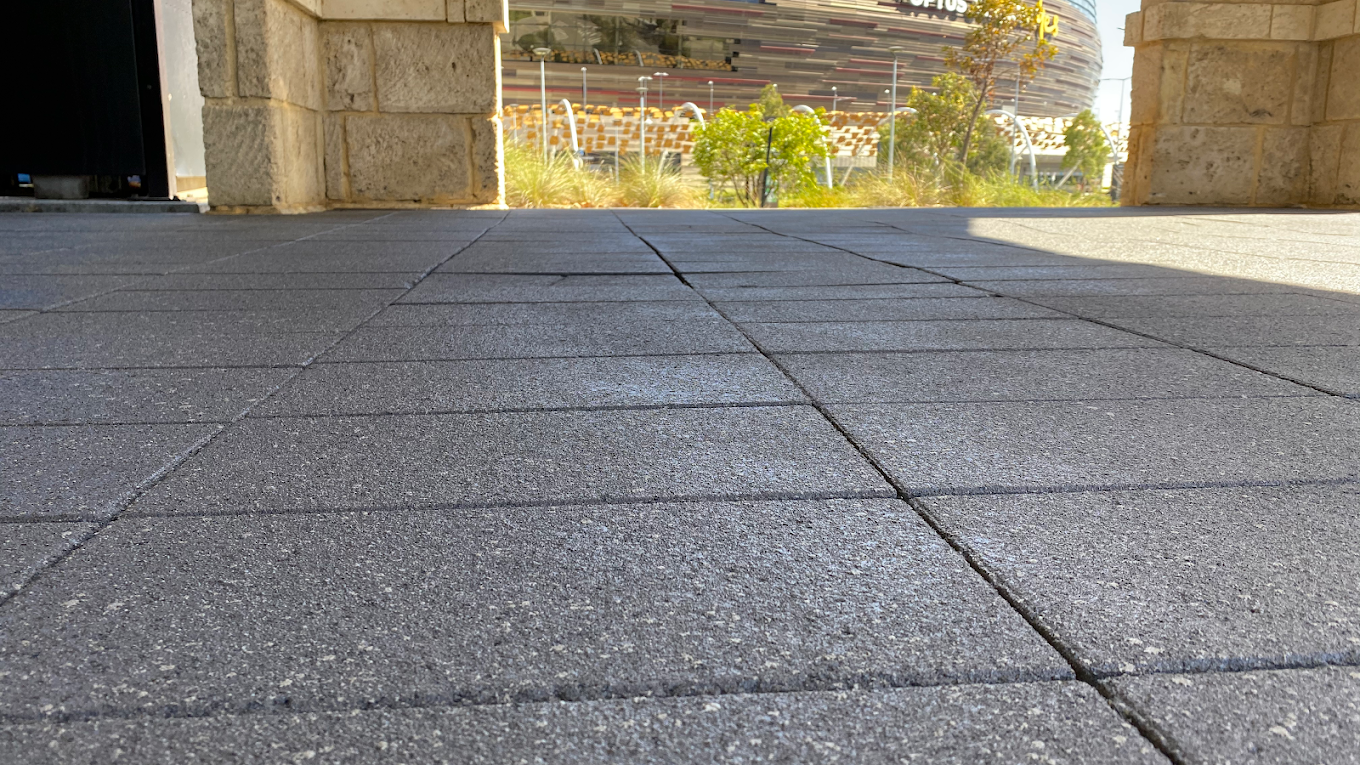 Charcoal exposed aggregate style surface photographed at ground level near Optus Stadium in Perth