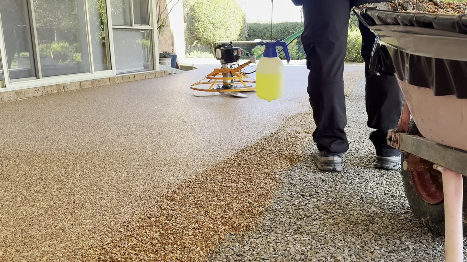 Golden Vuba resin-bound stone trowelled smooth beside loose aggregate on a Perth driveway mid-install
