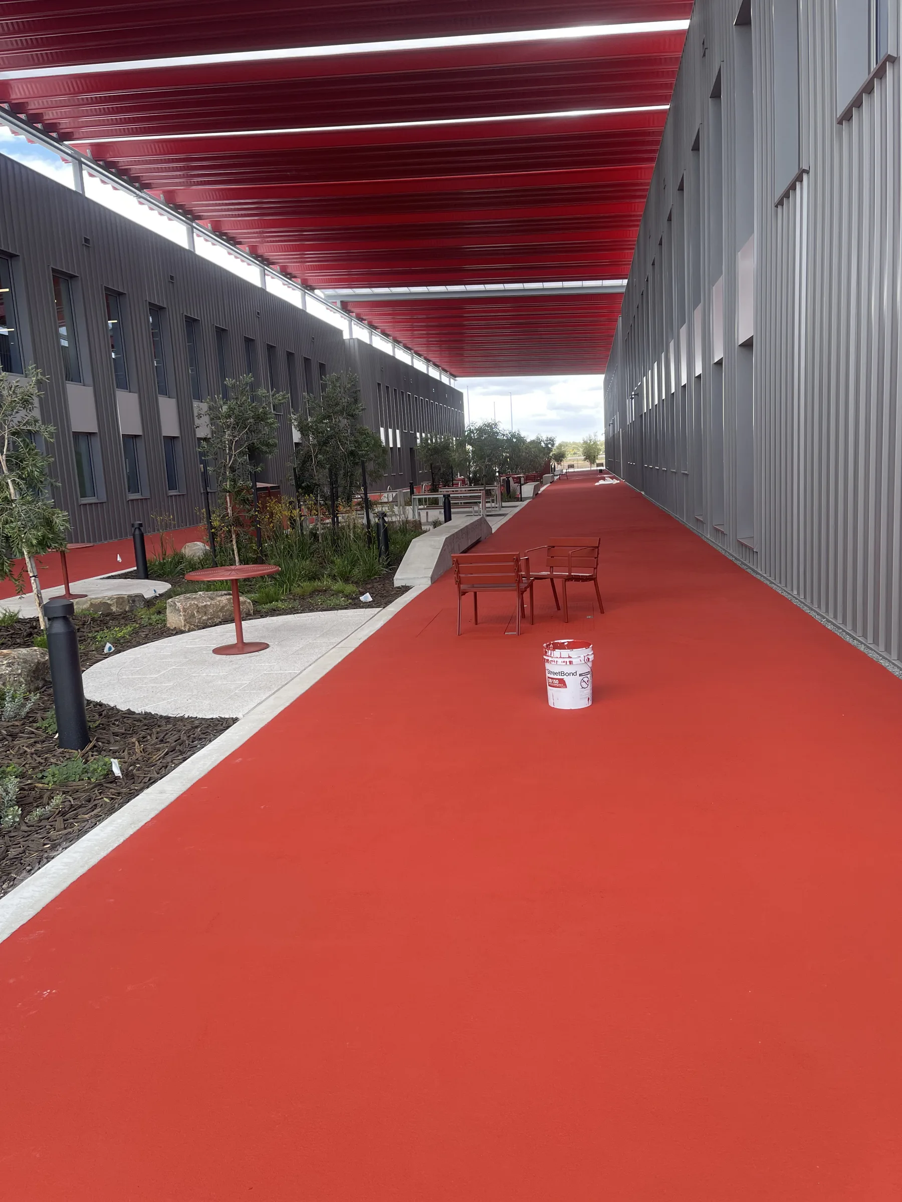 Long red StreetBond covered walkway running between two grey commercial buildings under a red roof