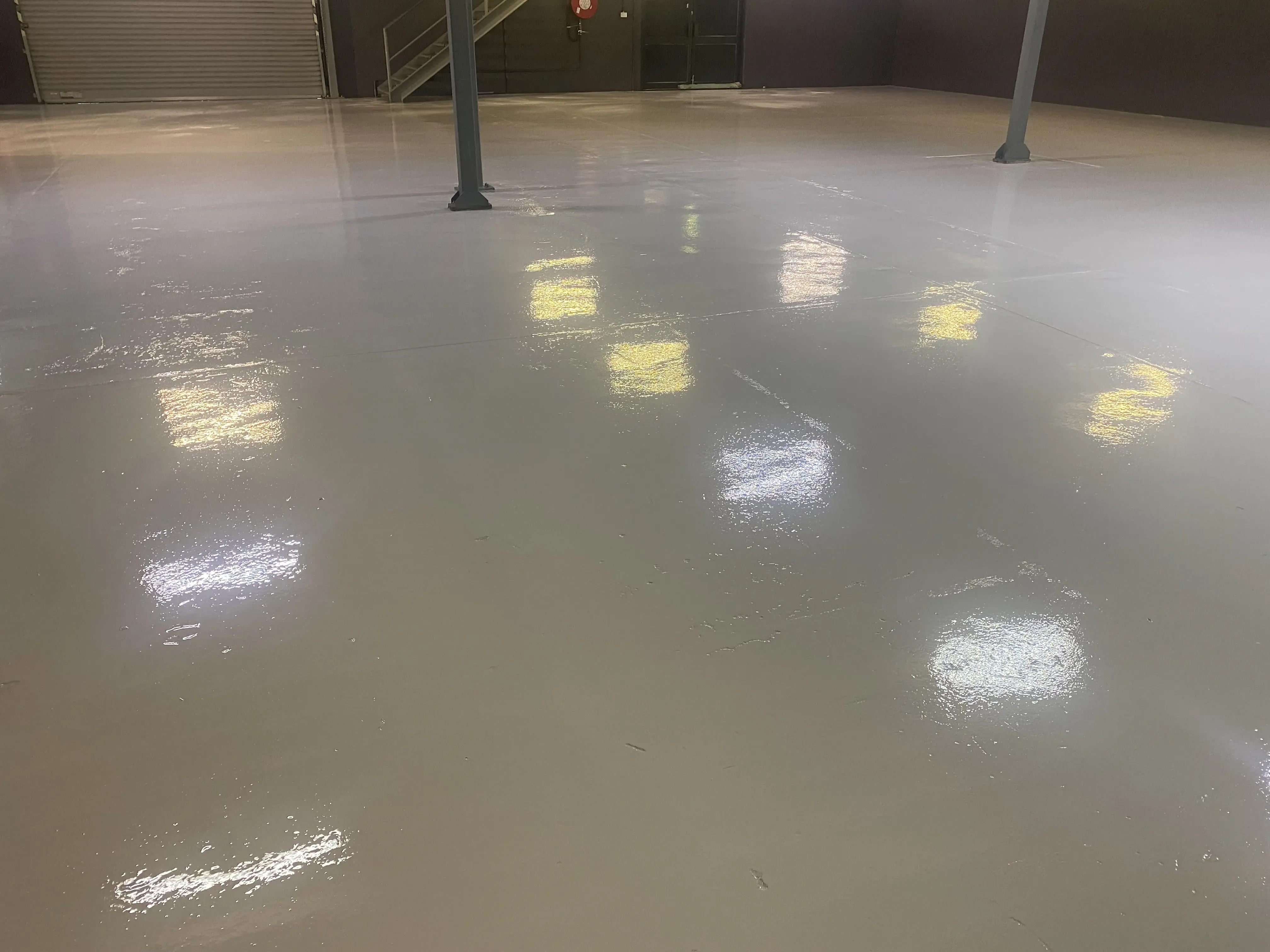 Plain solid-colour epoxy floor with a smooth satin clear topcoat in a garage or workshop setting