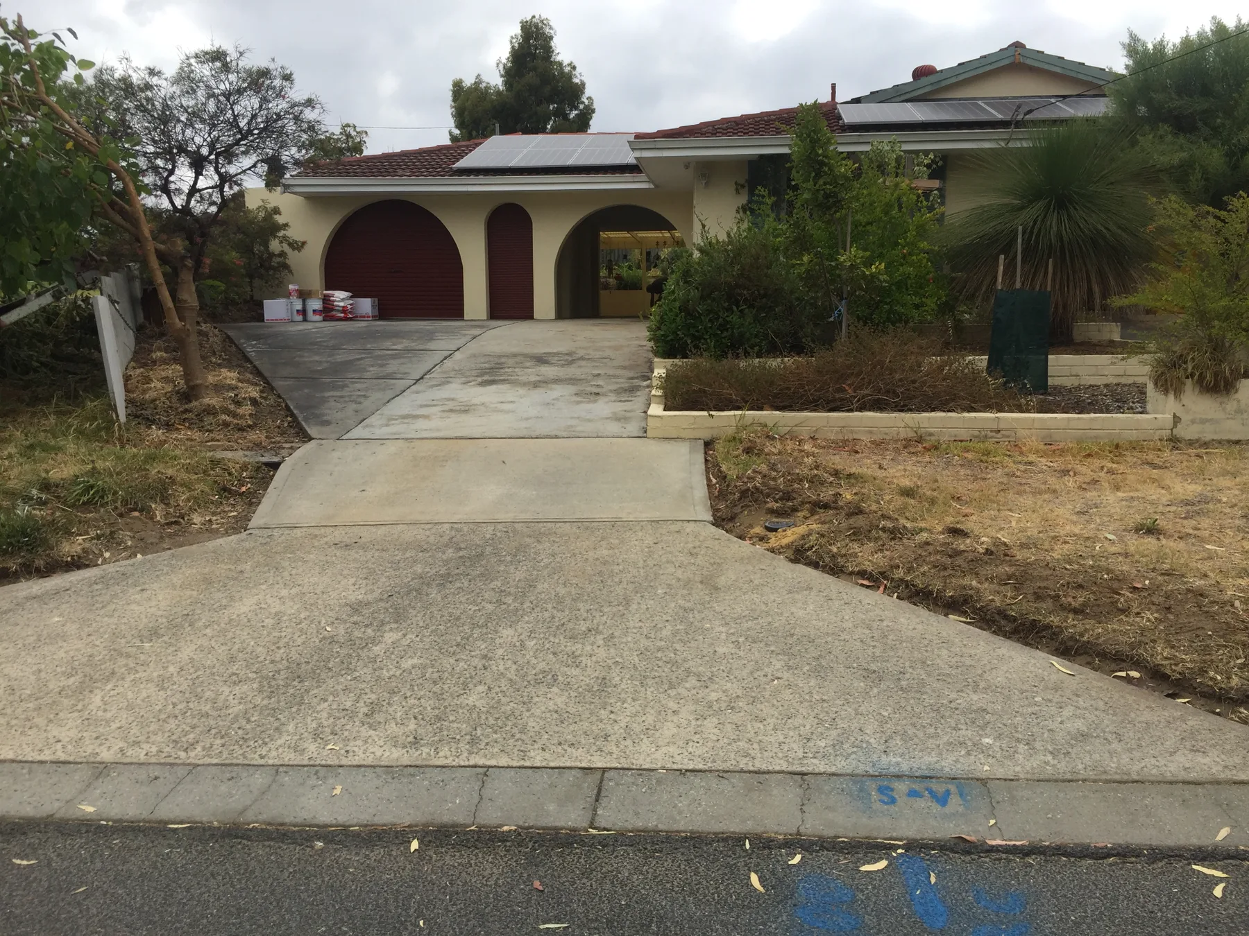 Tired grey concrete driveway and front path before spray-on paving, stained and patchy