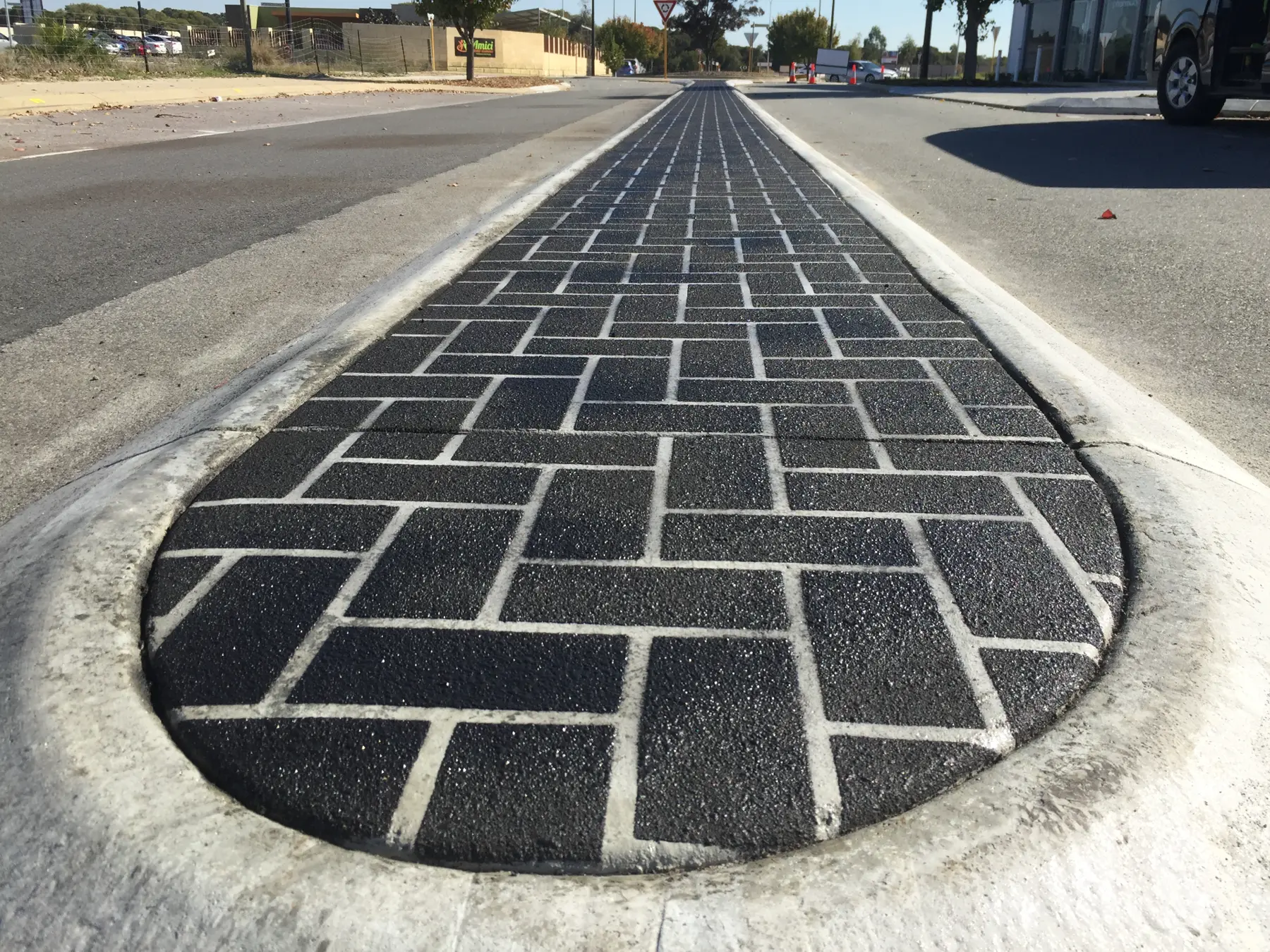 Close view of black stencil concrete brick pattern with white joint lines on a road median
