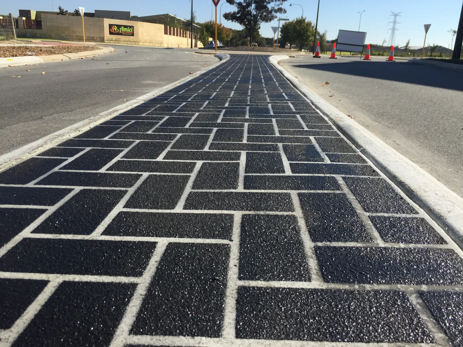 Low-angle view of a black stencil concrete brick-pattern median with crisp white joints