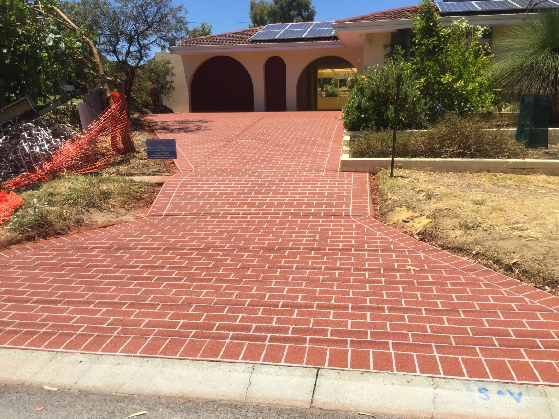 The same driveway and path after red brick-pattern spray-on paving with white joint lines